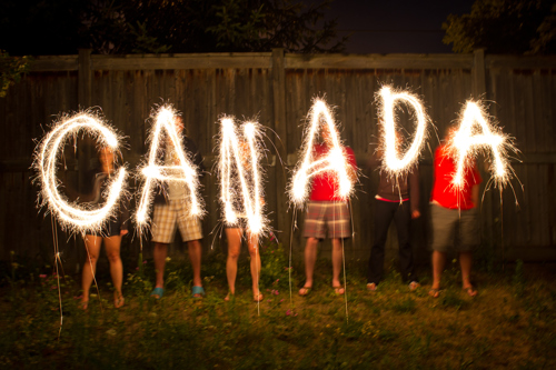 People holding sparklers that spell out C A N A D A